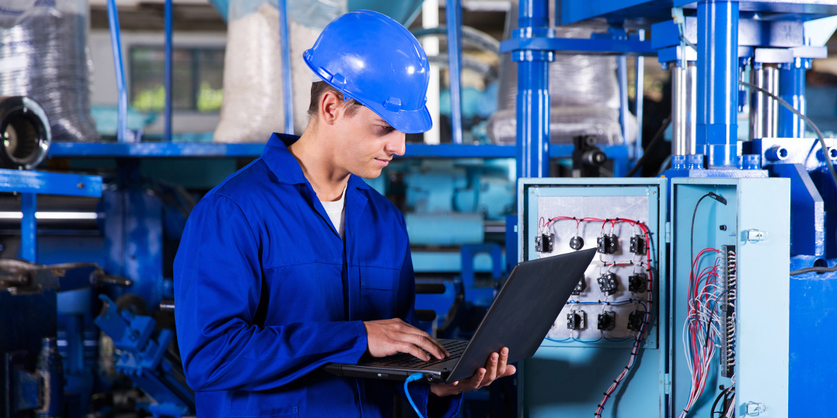 industrial programmer checking control box status with laptop computer